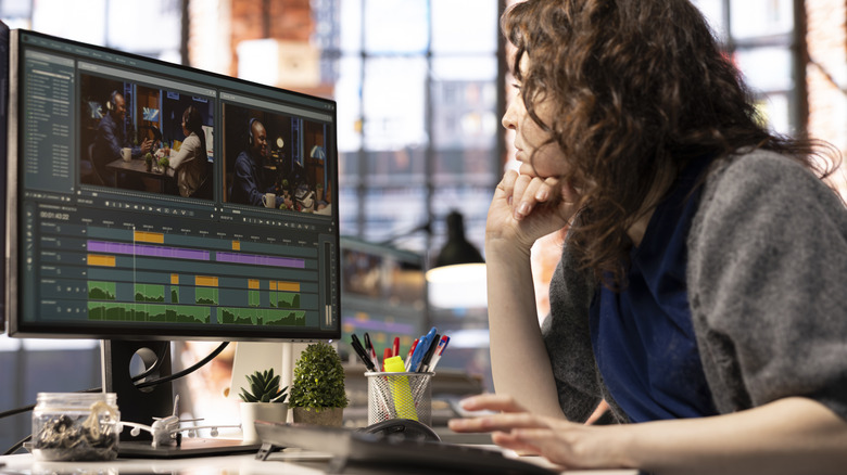 A person sits in front of a computer editing a video timeline.