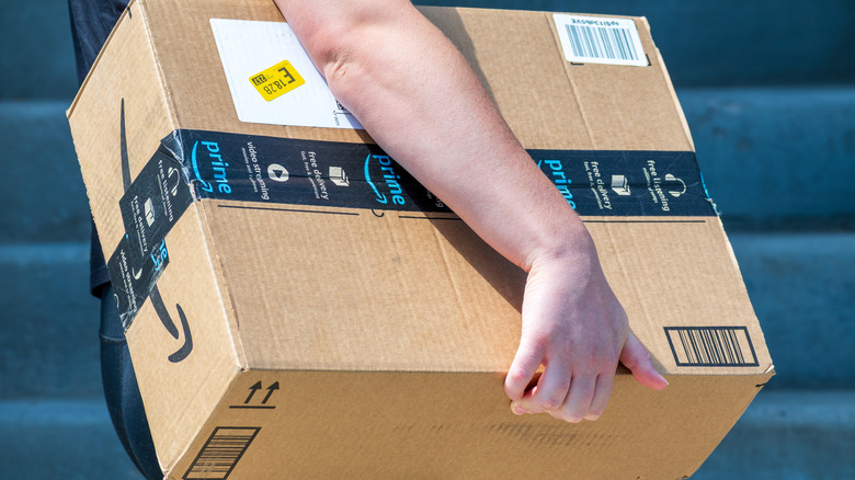 Person carrying Amazon cardboard package