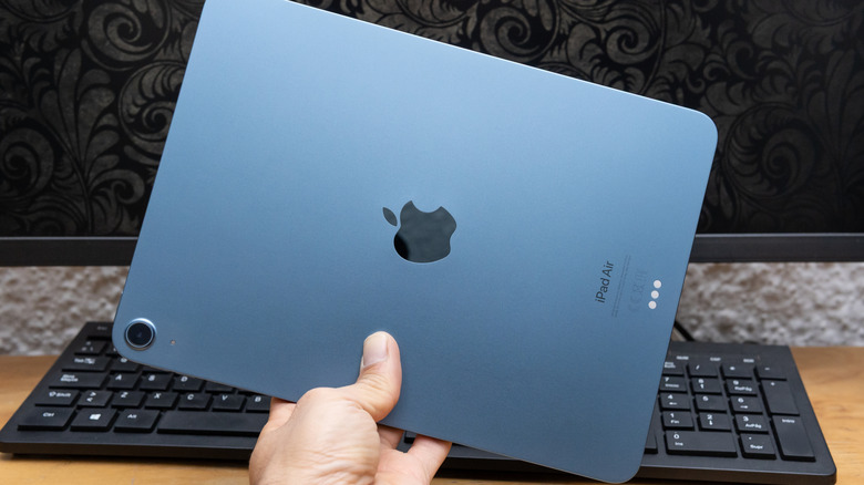 The back of an iPad Air held in front of a keyboard and monitor.