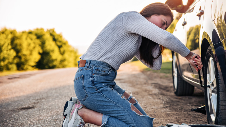 A woman trying to repair her car's wheel