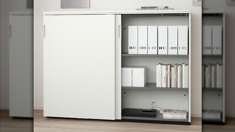 A white sliding cabinet with a compartment holding files and documents.