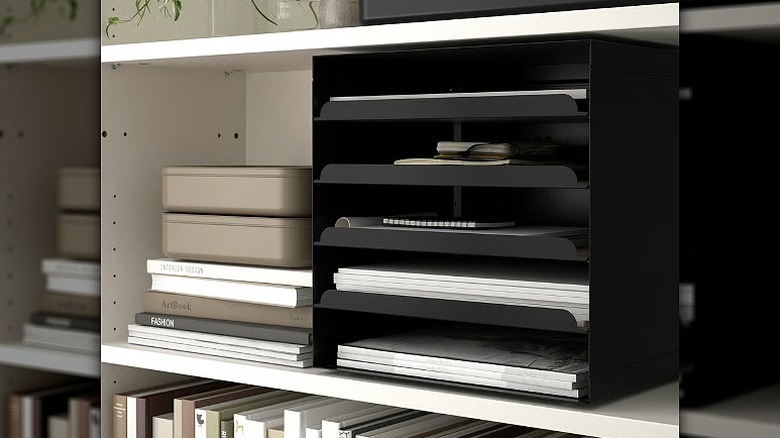 Black letter tray holding multiple papers and files placed in a shelf.