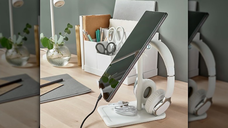 Tablet mounted on a holder with a headphone hooked on the back.