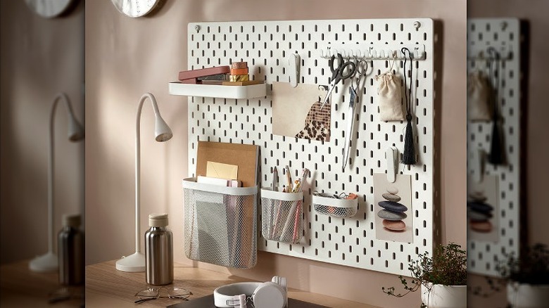 White pegboard holding multiple small accessories and pockets mounted on a wall.