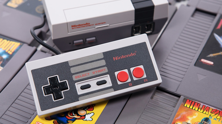 The NES Controller placed next to the console on top of a bunch of game cartridges