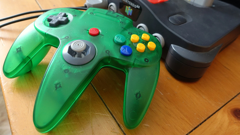 A green Nintendo 64 controller next to a black console