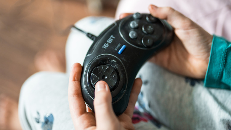 A pair of hands holding the Sega Genesis Six Button Control Pad
