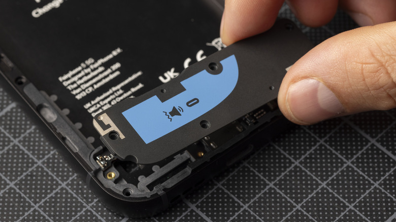 A hand holds the speaker module of a Fairphone modular phone.