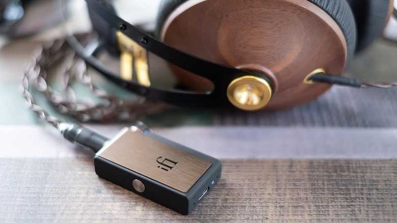 An iFi GO portable Bluetooth DAC next to a set of premium over-ear headphones.