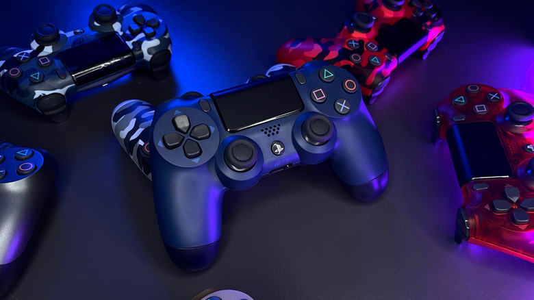 Multiple PlayStation DualShock 4 controllers in various colors against a smooth dark surface