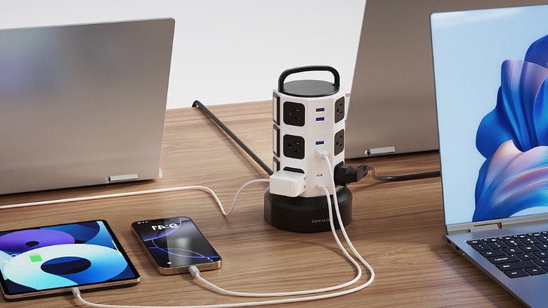 Different devices connected to a power strip tower on a desk