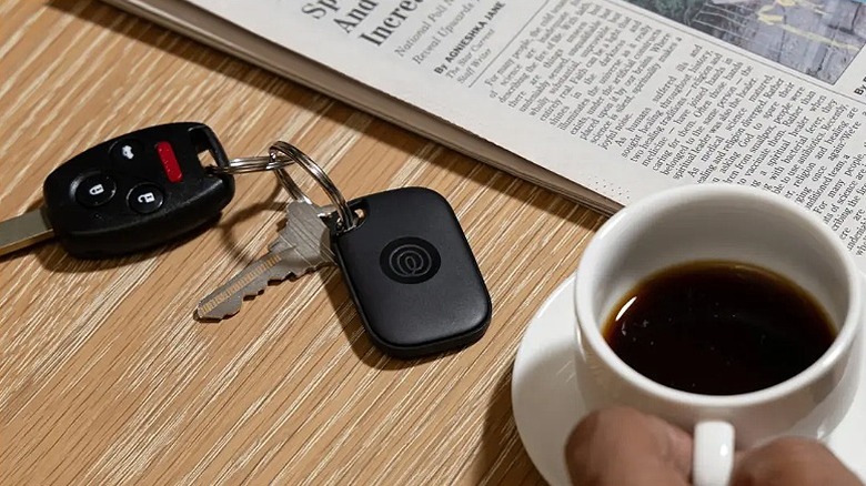 Tile Pro connected to car keys placed on a table with newspaper and coffee