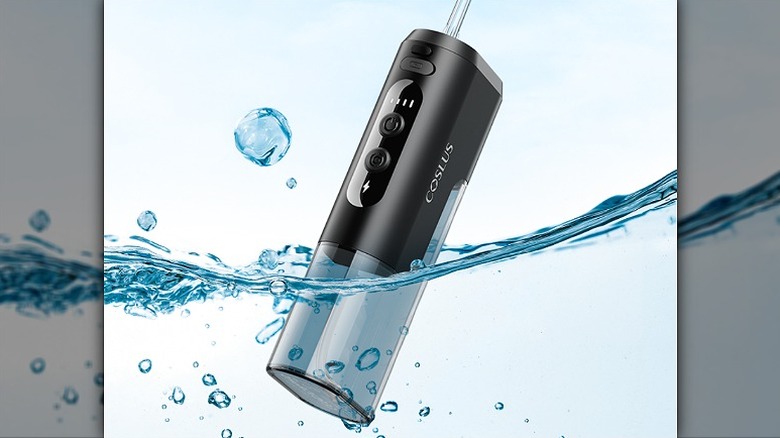 Water flosser submerged halfway into clear water.