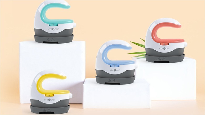 Three pieces of Htvront heat press placed on elevated white surfaces with one placed on the floor.