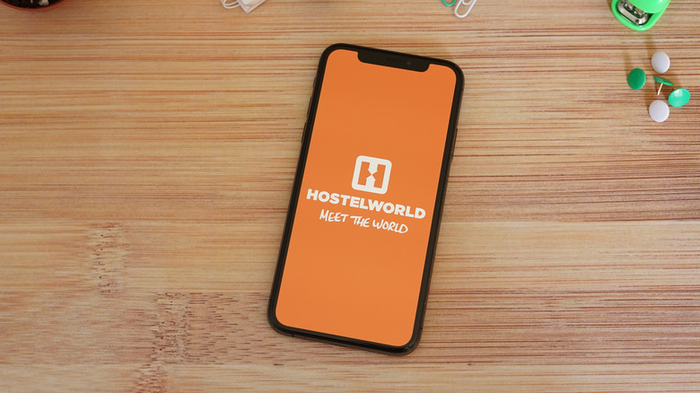 The Hostelworld logo on a phone placed on a wooden desk