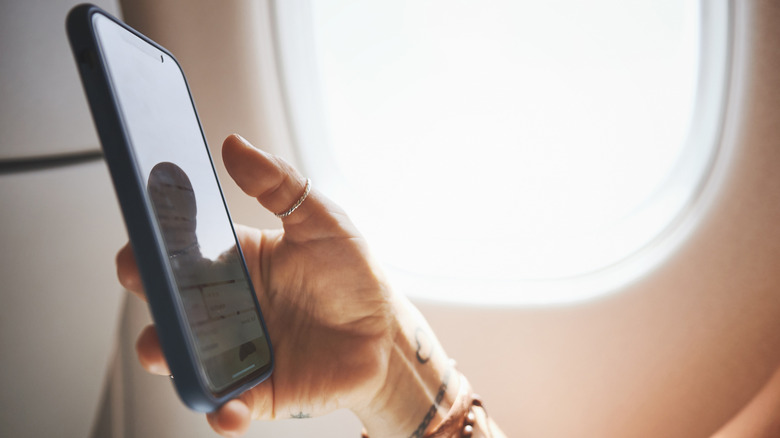 A person holding a cell phone on a plane