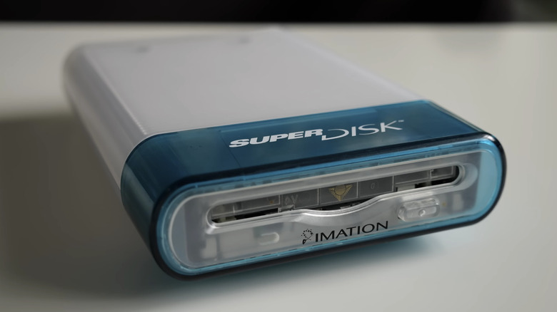 An Imation SuperDisk drive isolated on a surface with a blurred background.