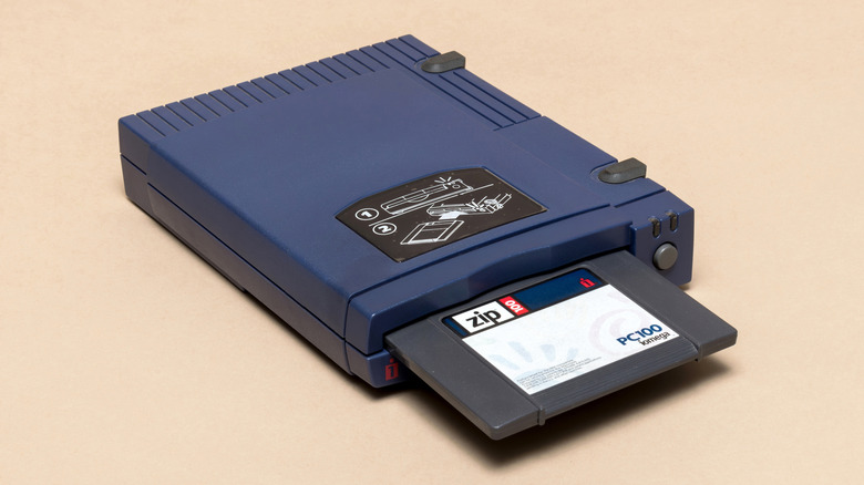 An Iomega Zip drive with a disk partially inserted into it on a beige background.