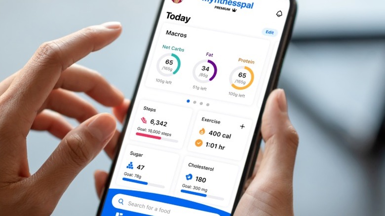 A person holding an iPhone showing the MyFitnessPal app