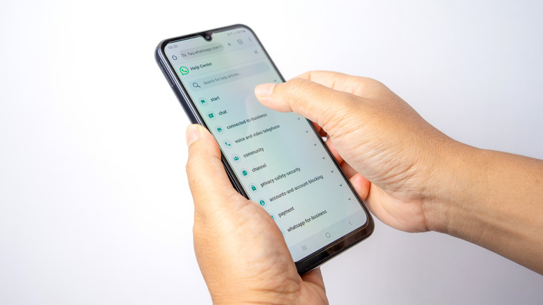 Hands holding a smartphone browsing the WhatsApp