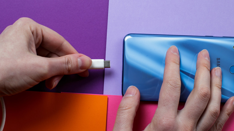 Close up of hands connecting the charger to the phone Samsung A30.