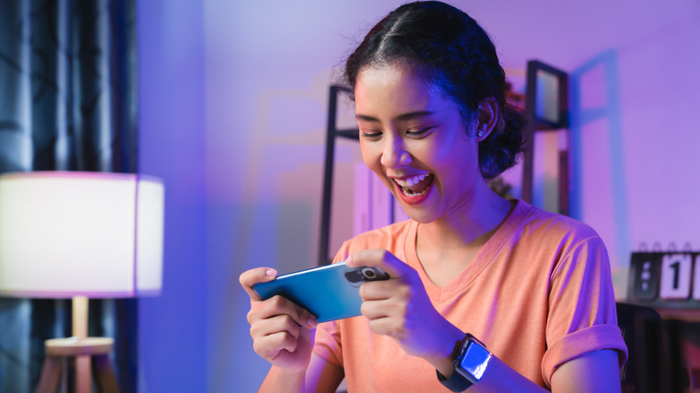 Woman wearing headset and playing online game on smartphone