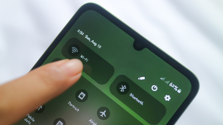 Smartphone screen displays a quick menu, focus on the finger touching the WiFi icon.