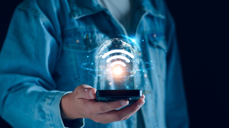 Man holding out a phone with the Wi-Fi symbol floating above it in a bubble