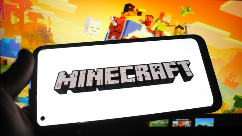 Minecraft logo on a smartphone with a Minecraft website in the background