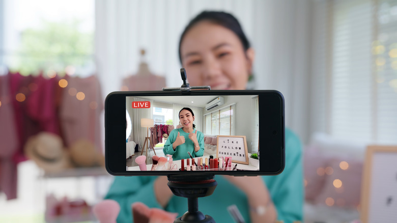 Telephone on a tripod recording a female influencer on a livestream