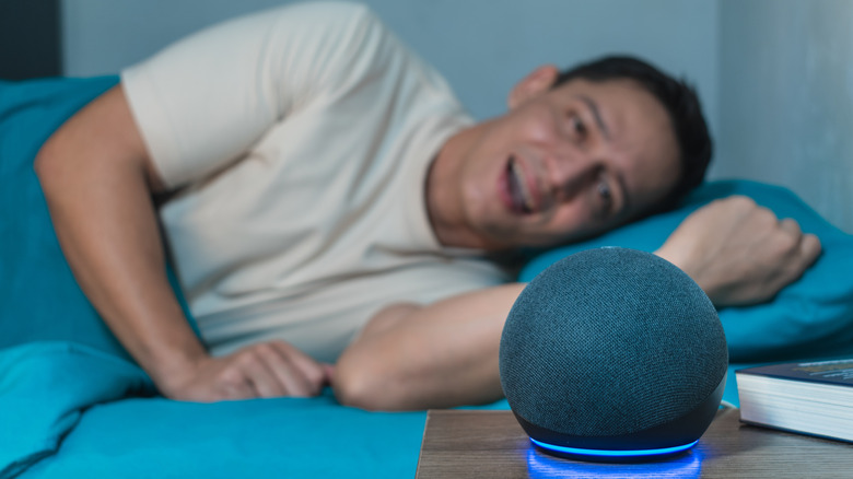 Man lying on his bed talking to the Amazon Alexa Echo Dot voice assistant