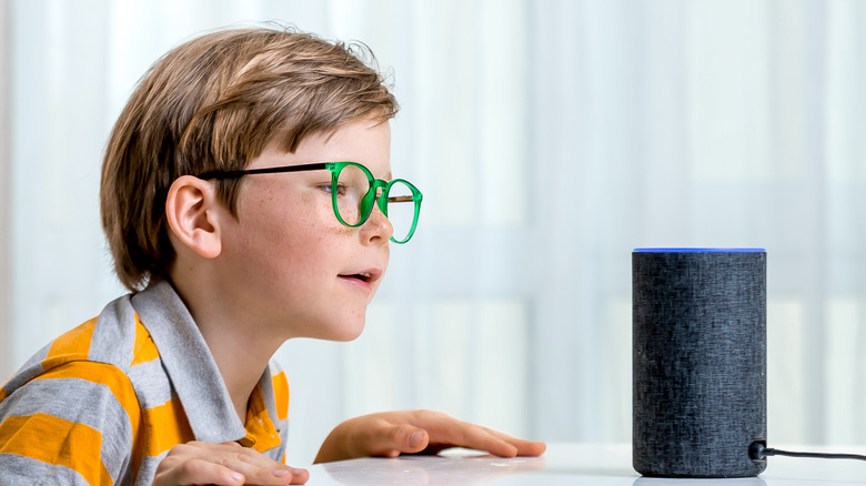 Little kid talking to talking to Amazon Alexa Echo Dot placed on a table