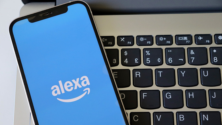 Alexa logo displayed on smartphone screen with a laptop keyboard in the background