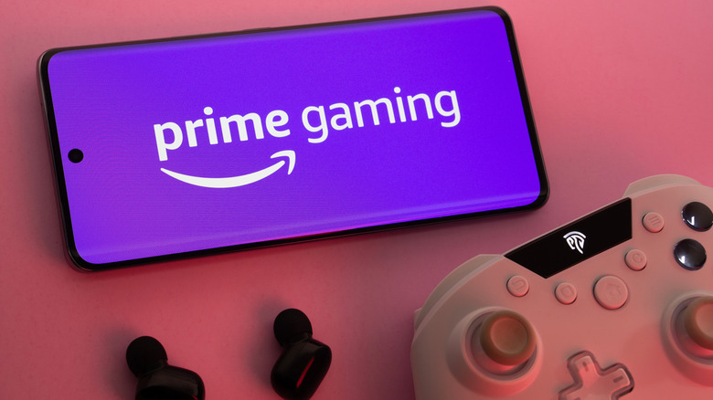 A smartphone with Prime Gaming logo placed alongside a controller and earbuds