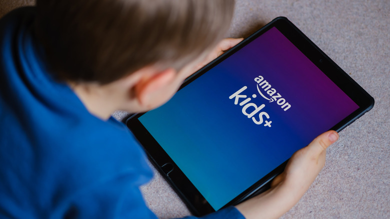 A child holding iPad with Amazon Kids+ logo on the screen