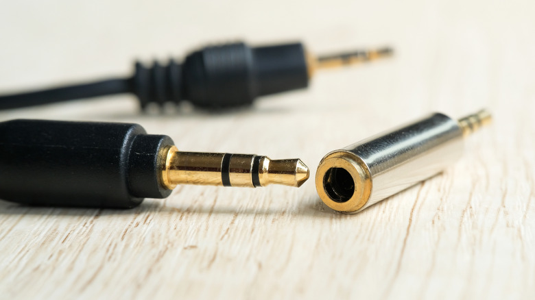 Close-up of a headphone cable with an adapter on a wooden service.