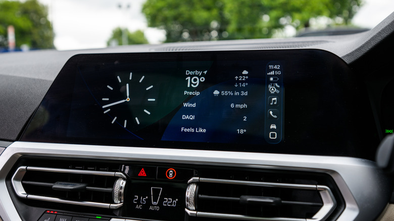 A vehicle's infotainment screen displaying the new Clock and Weather widgets available for CarPlay in iOS 26