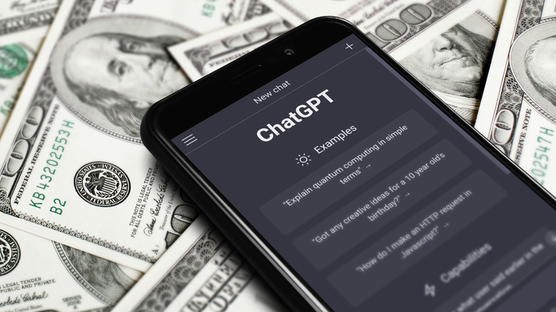 A cellphone displaying ChatGPT as the device sits on top of a several hundred dollar bills