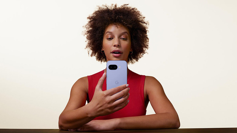 A woman sitting and holding the Google Pixel 9a.