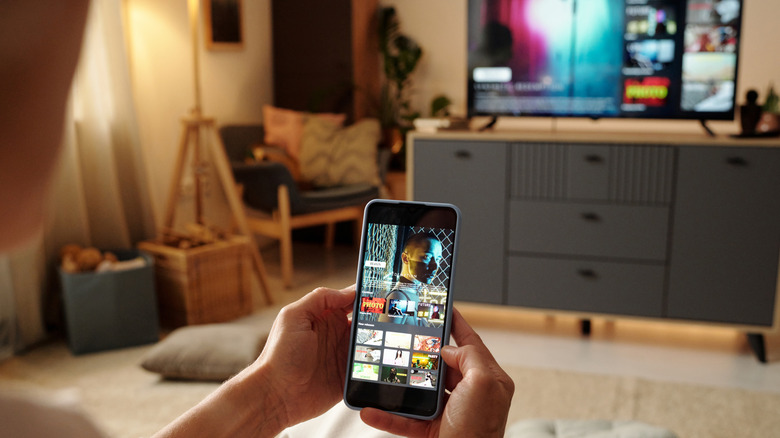Hands holding a smart phone casting to a smart TV