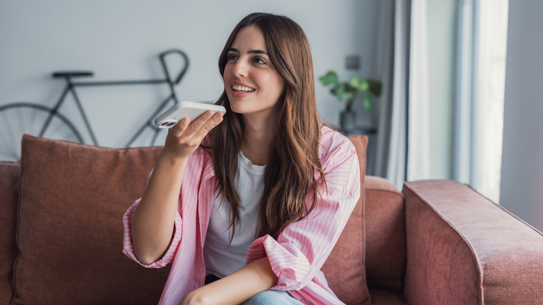 A woman giving commands to a mobile voice assistant while at home
