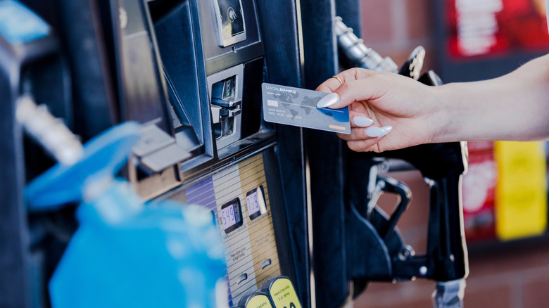 A person inserting a credit card into a gas station pump.