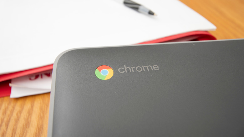 A Chromebook placed in front of a binder, pen, and paper.