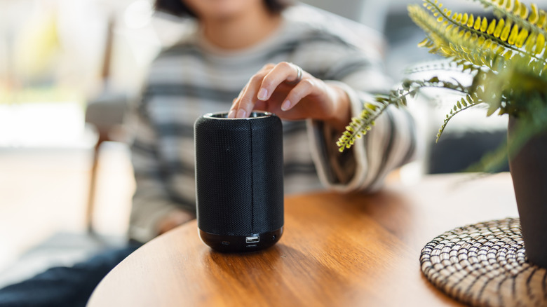 Smart speaker on table with hand touching top