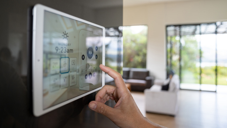 Smart home tablet screen showing smart home controls with hand in front