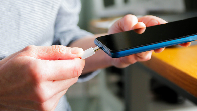 a man plugging in his phone to charge the battery