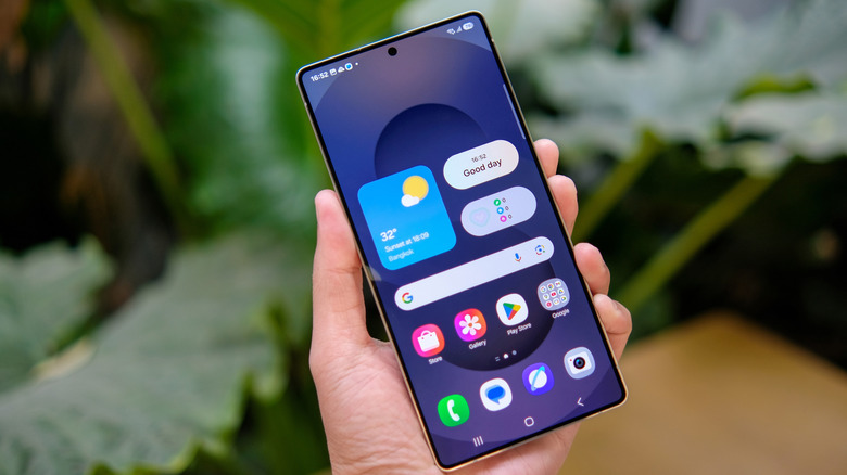 a hand holding a Samsung smartphone with apps visible