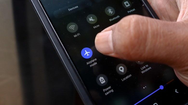 a person holding their phone and turning on airplane mode