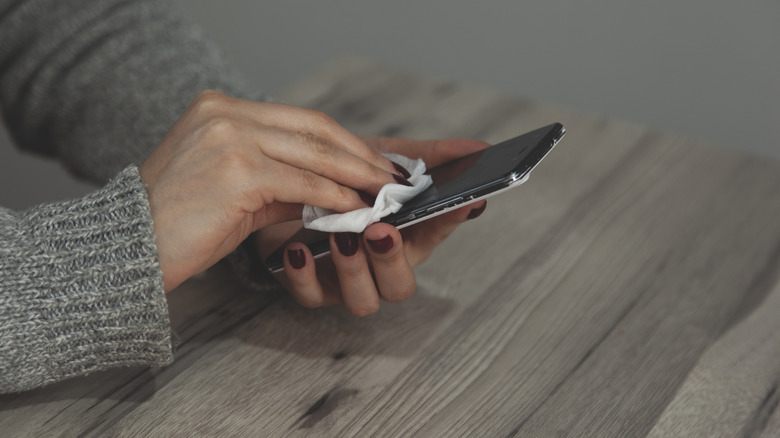 A woman's hands cleaning a phone screen.