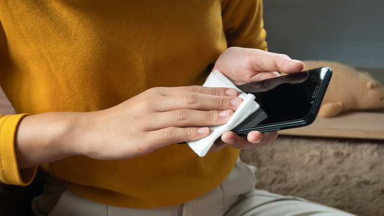 A woman cleaning a phone screen with a cloth.